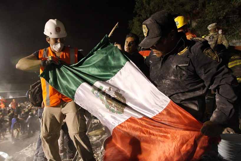 Trabajadores de rescate desplegando bandera mexicana.