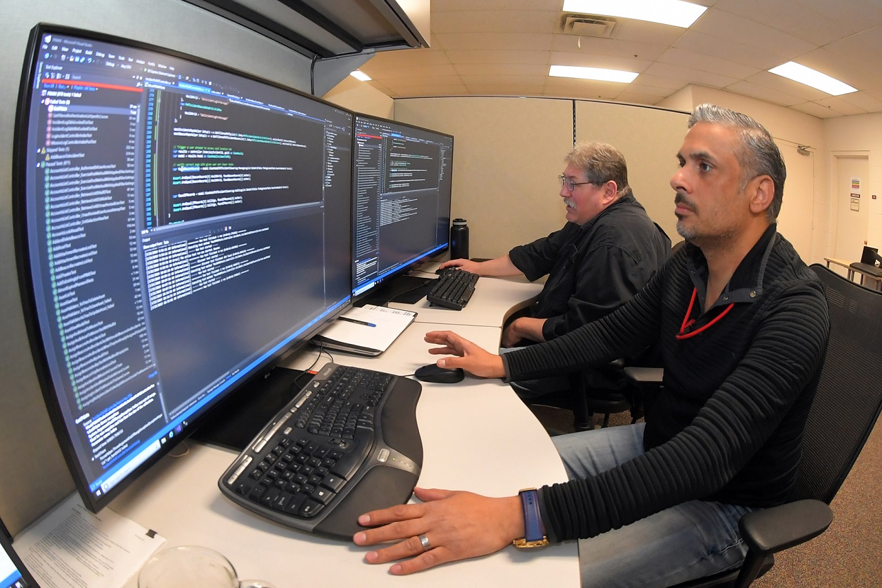 (Left to right) Mark Morris and Raheem Alhamdani, software engineers, 517th Software Engineering Squadron, perform paired programming March 25, 2019, at Hill Air Force Base, Utah. This new paired programming approach is part of a new workflow system and software development methodology to significantly reduce the time it takes to deliver software to customers. (U.S. Air Force photo by Todd Cromar)
