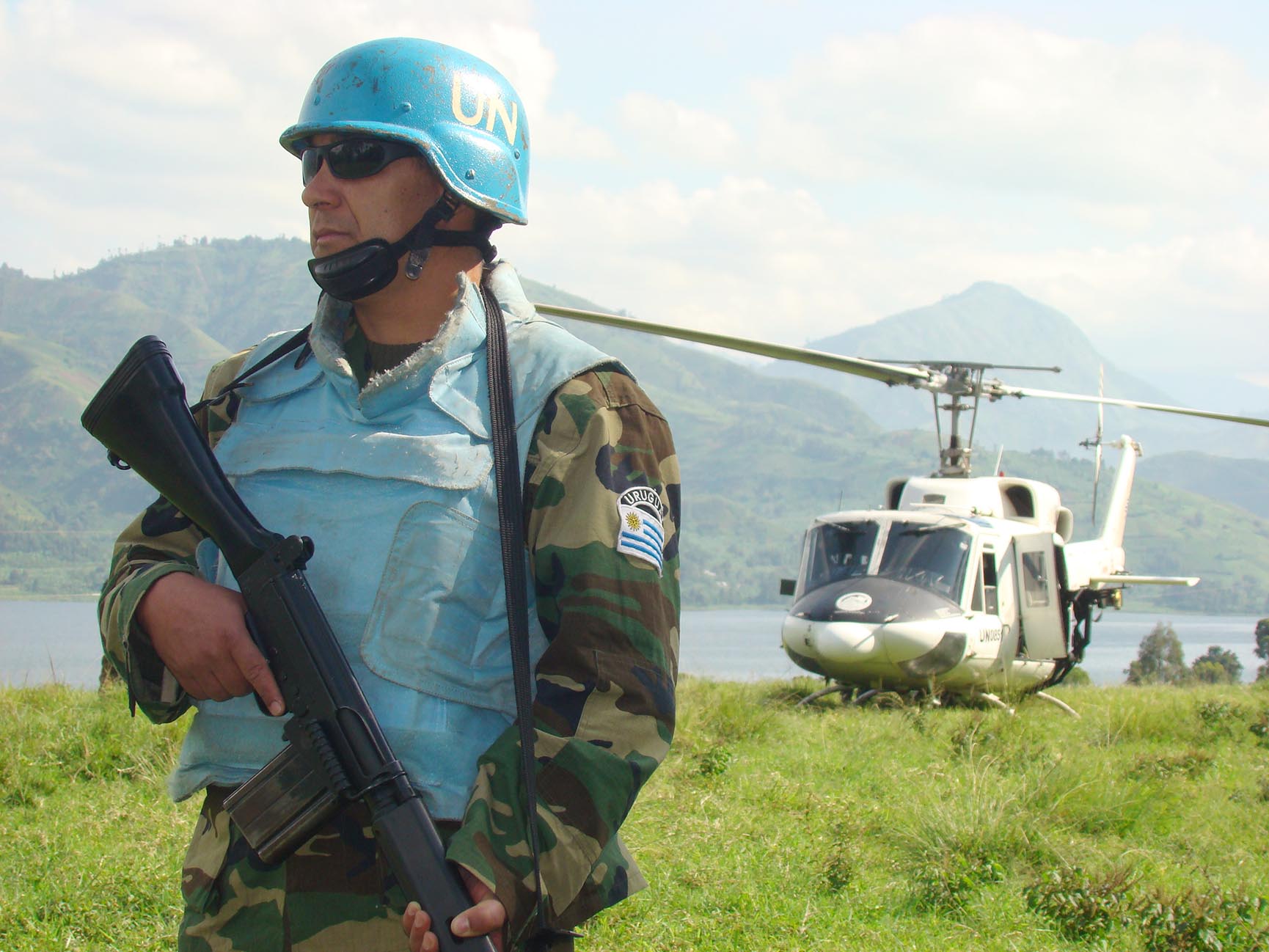 A Uruguayan UN member stands at the ready with his helicopter in the background.